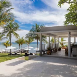 pectacular ocean view from the bar of a luxury resort in Lombok, featuring a serene beachfront, crystal-clear waters, and the stunning ocean in the background