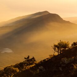 Golden sunrise over Mount Rinjani, Lombok, casting light over the volcanic slopes, creating a stunning trekking experience in Indonesia.