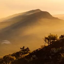 Golden sunrise over Mount Rinjani, Lombok, casting light over the volcanic slopes, creating a stunning trekking experience in Indonesia.