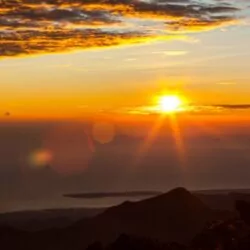 A breathtaking sunrise view from Mount Rinjani, Lombok, Indonesia, overlooking the ocean and mountain peaks – a must-see for trekkers.