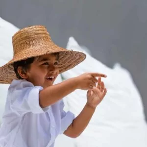 Happy child in a straw hat and white shirt playing at a luxury family resort in Lombok