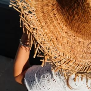 Back view of a child in a woven straw hat and white eyelet top, enjoying the sun at a luxury family resort in Lombok