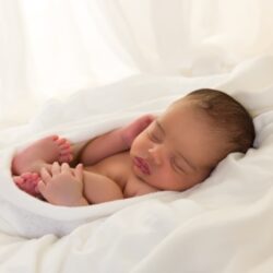 Peaceful newborn sleeping in soft white blanket after babymoon in Lombok