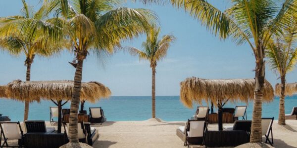 Romantic beachfront setting in Lombok with palm trees, luxury sunbeds, and turquoise ocean – perfect for an anniversary getaway